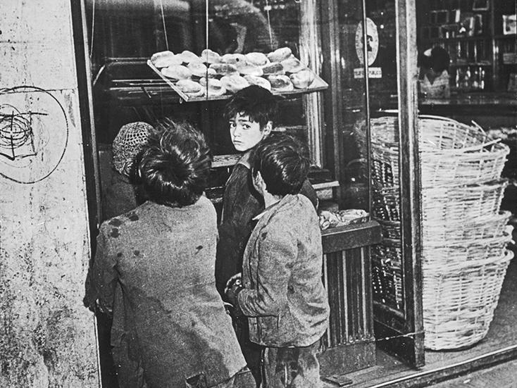 Grupo de niños frente vitrina de una panadería