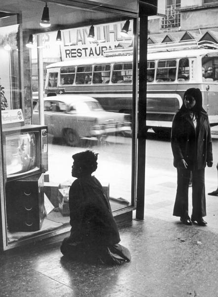 Niño mirando un televisor ubicado en vitrina de local comercial