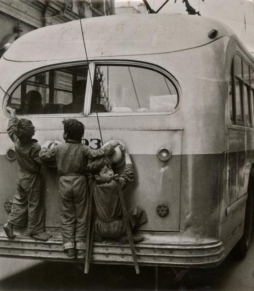 Niños colgados de la parte trasera de un trolebús